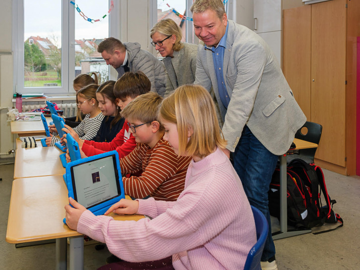 Jens Hanschke (vorn), Annegret Otte und Dennis Heinze lassen sich von den Schülern ihre iPads zeigen. Die blauen Schutzhüllen dienen gleichzeitig als Aussteller für die Geräte. 