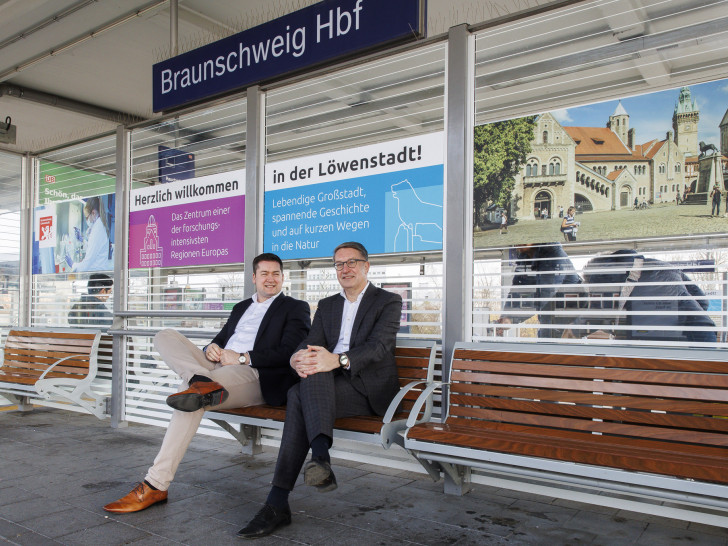 Oberbürgermeister Dr. Thorsten Kornblum und Gerold Leppa, Geschäftsführer des Stadtmarketings, präsentieren die neuen Beklebungen an den Sitzeinhausungen am Hauptbahnhof. 