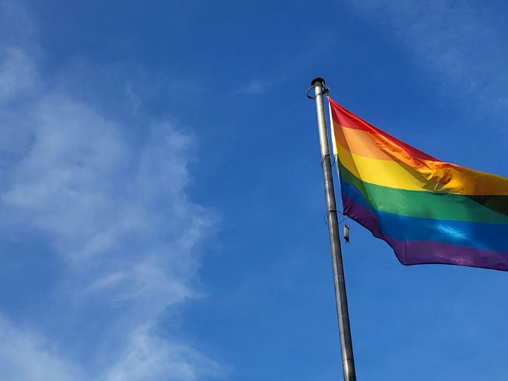 Die Regenbogenflagge weht vor dem Rathaus im Wind.