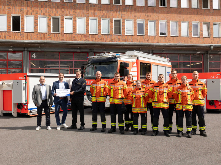 Jens-Folker Huismann und Christoph Mrasek von der Öffentlichen bei der Scheckübergabe an Torge Malchau und die aktuellen Auszubildenden der Braunschweiger Feuerwehr (von links nach rechts).