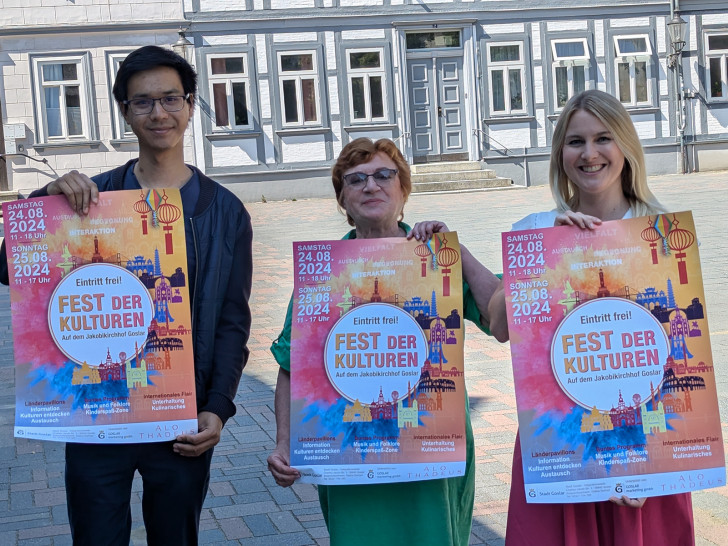 Auf dem Jakobikirchhof und damit direkt am Ort des Geschehens wird das diesjährige Plakat für das Fest der Kulturen durch Mara-Lena Macke (re.), Fachdienstleiterin Bildung und Soziales der Stadt Goslar, Galina Gerhart (Mitte), Integrationsbeauftragte der Stadt Goslar und Bundesfreiwilligendienstler Dang Khoa Chau (li.) vorgestellt.