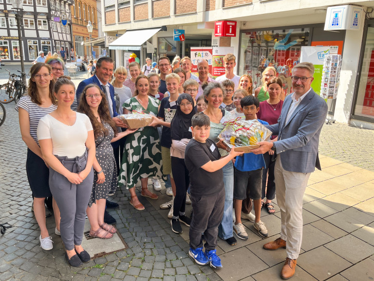 Wirtschaftsdezernent Gerold Leppa (vorne rechts) und Torsten Glaser, Leiter des Regionales Landesamt für Schule und Bildung Braunschweig, übergaben die Präsentkörbe an Schülerinnen und Schüler der Fairtrade AG am Gymnasium Ricarda-Huch-Schule. Im Hintergrund das von ihnen gestaltete Schaufenster der Tourist-Info (Kleine Burg 14).