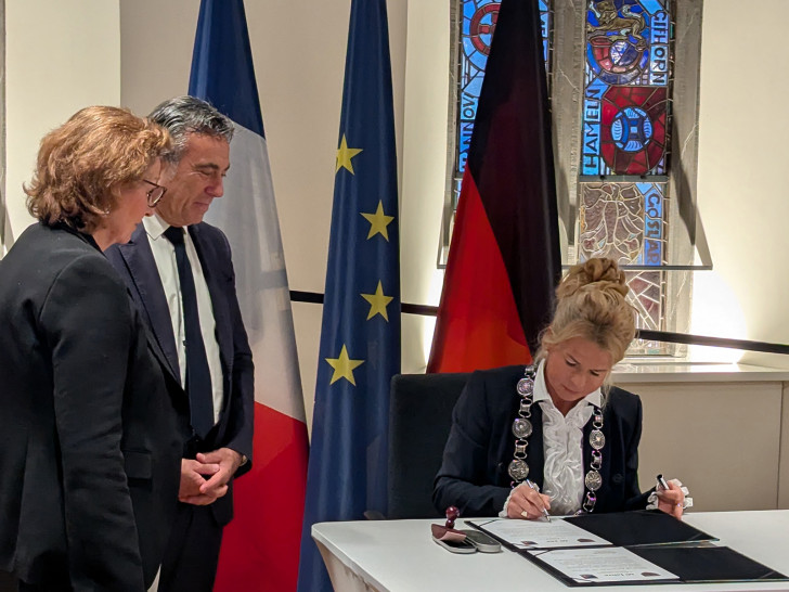 Oberbürgermeisterin Urte Schwerdtner (re.) unterzeichnet vor Arcachons Bürgermeister Yves Foulon (Mitte) die neue Partnerschaftsurkunde. Dagmar Mönnecke-Koroma (li.), Stadt Goslar, übersetzte während der gesamten Veranstaltung.