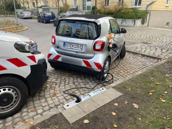 Der Ladevorgang eines Elektrofahrzeugs über den Bordstein.