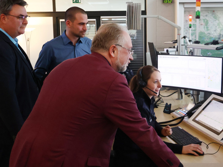 Lars Oehmke (Geschäftsführer Rettungsdienst Cuxland gGmbH), Dr. Benjamin Junge (Ärztlicher Leiter des Rettungsdienstes im Landkreis Cuxhaven) und Ulrich Bruns (Fachdienstleiter Rettungswesen beim Landkreis Goslar) blicken in der Goslarer Leitstelle Laura Jodat über die Schulter.