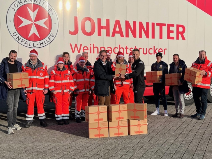 Eintrachts Co-Trainer Marc Pfitzner übergibt eines der elf Pakete an Johanniter-Landesvorstand Hannes Wendler. Bildnachweis: Johanniter/Lena Kopetz.