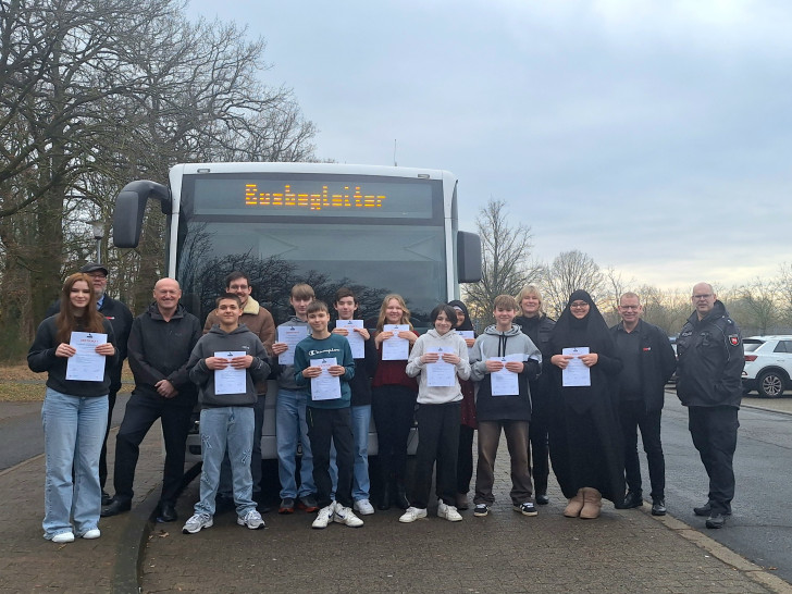 Neben den Achtklässlern stehen Knut Hirschfeld (Busfahrer), Ulf Blanke (Gesamtschuldirektor), Marc Klinkert (Jahrgangsleiter), Silke Hitschfeld (Polizei), Dirk Rodenstein (Fahrdienstleiter WVG) und Jens Oertelt (Polizei).