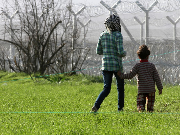 Flüchtlinge vor einem Grenzzaun (Archiv)