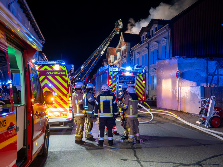 Die Einsatzkräfte vor dem brennenden Mehrfamilienhaus.