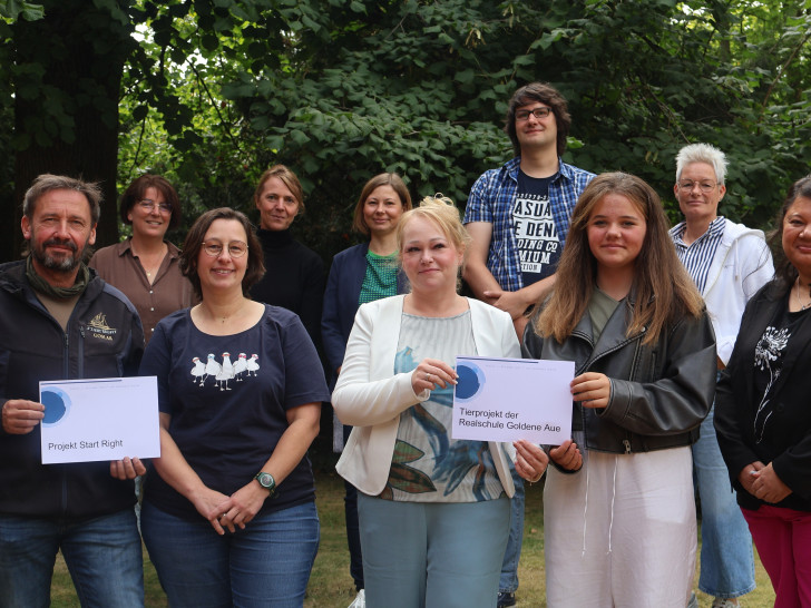 Die Vergabekommission für „… die paar Cent!“, bestehend aus (hintere Reihe im Bild, von links) Katja Sdralek, Nicole Schwarzenberger, Stephanie Schwarz, Sascha Riedl und Birgit Römer, überreicht die Spendengelder  Die vordere Reihe zeigt die Projektverantwortlichen sowie die Mitarbeiterinnen des Landkreises Goslar, die jeweils diese Vorschläge eingereicht haben (von links): Thomas Derer („Start Right“), Christine Lipinski, Isabel Barfus, Charlotte Böttger (beide verantwortlich für das Tierprojekt der Goldenen Aue), und Jacqueline Diercks.