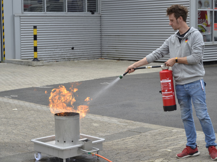 Ein Teilnehmer trainiert den sicheren Umgang mit dem Feuerlöscher an einem simulierten Brand.