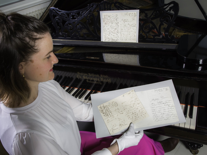 Dr. Antje Becker mit einer Auswahl an Clara Schumann-Autographen am Flügel der Pianistin.