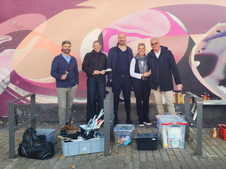 Künstler Sebastian Roese, Josephine Stein (Leiterin Handel und Zentren im Bereich Wirtschaftsförderung der WMG), Michael Ernst (Vorstandsmitglied des CMT und Centermanager der Designer Outlets Wolfsburg), Svenja Hohnstock (Vorstandsmitglied des CMT und Geschäftsführerin der Hohnstock GmbH und der BRAINTEC GmbH) und Frank Hitzschke (Bereichsleiter Citymanagement der WMG) kurz vor der Fertigstellung vor dem neuen Wandbild (v. li.).