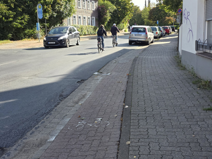 Die Radfahrer müssen links an dem im Parkverbot stehenden Kleinwagen vorbeifahren, da die Zufahrt zum Radweg erst dahinter verläuft.