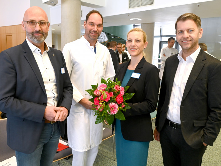 Charlotte Bettina Boettcher (2.v.r.) freut sich über die nette Begrüßung durch Klinikumsdirektor André Koch (v.l.), den Ärztlichen Direktor Prof. Dr. Nils Homann und Oberbürgermeister Dennis Weilmann.