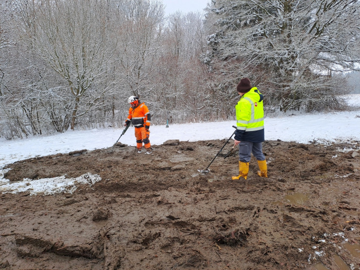 Fachleute bei der Sondierung des ausgehobenen Teichschlamms auf der Wiese.