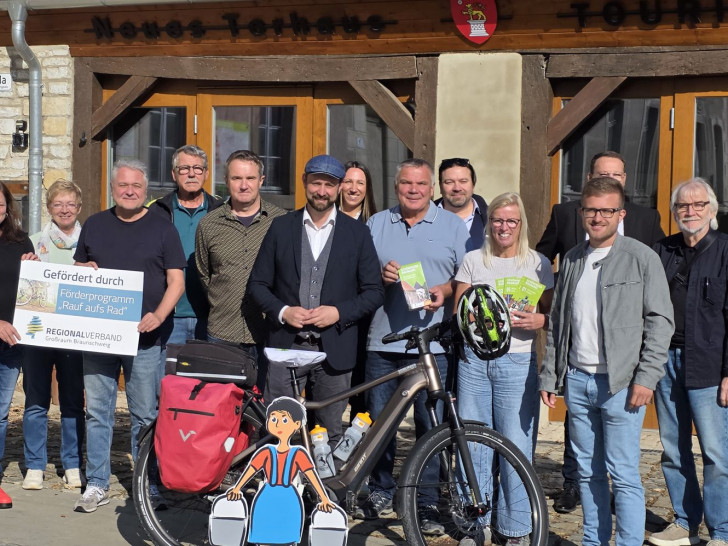 Bürgermeister Malte Schneider (Mitte) mit den Projektbeteiligten die Schönin- ger Radnadel vor der Schöninger Touristmusinformation im Torhaus.