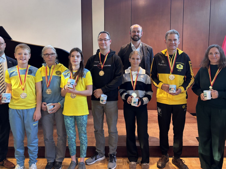Enno Deuter, Vorsitzender der DLRG-Ortsgruppe Schöningen, und Bürgermeister Malte Schneider (2. Reihe) mit den Champions des 12-Stunden-Schwimmens 2026. 