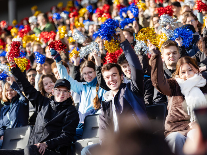 Die neuen Studenten der TU Braunschweig wedeln mit glitzernden Pompons.