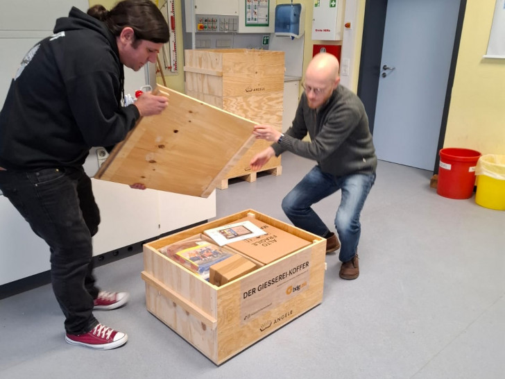 Die Lehrer Sebastian Pach (re.) und Dr. Alexander Witt öffnen einen Teil des „Koffers“, der die neue Schulgießerei enthält.