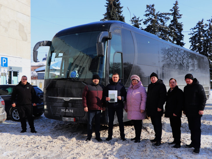 Vasyl Holovachko (links), Fahrer des Reisebus, und Oleksandr Kodola (Dritter von links), Bürgermeister der Stadt Nischyn, bei der Übergabe des Busses.
