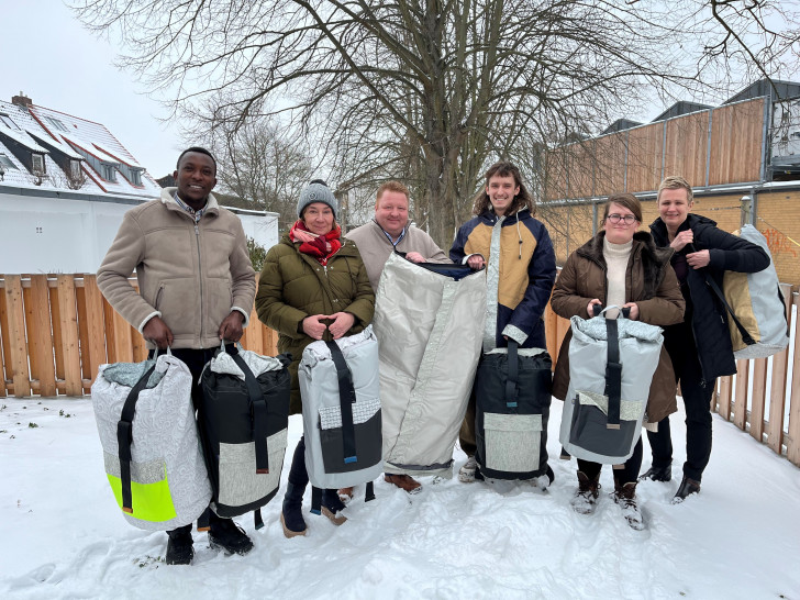 Desire Bararunyeretse (Tagestreff), Sabine Rieck (Ambulante Hilfe), Marc Wegner (Johanniter-Hilfsgemeinschaft), Ragnar Petzke und Alissa  Wittenfeld (beide Tagestreff), Nadine Boß (Regionalleitung Diakonische Gesellschaft Wohnen und Beraten) - Mitarbeiter im Tagestreff, Ragnar Petzke, präsentiert den Sheltersuit – Jacke, Schlaf- und Rucksack.