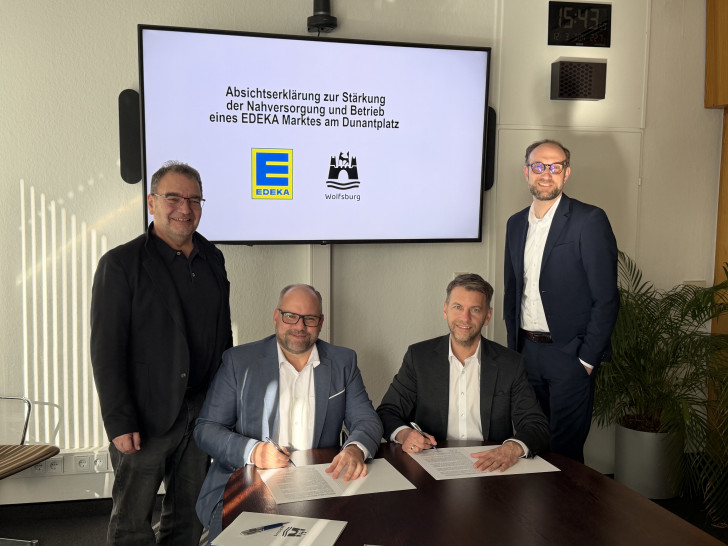 Oberbürgermeister Dennis Weilmann (2. v. re.) und Moritz Hoppe (Expansion Edeka Minden-Hannover) unterschreiben im Beisein von Jens Hofschröer (Stadtrat für Digitales und Wirtschaft sowie WMG-Geschäftsführer, rechts) und Sabah Enversen (Ortsbürgermeister Wolfsburg Mitte-West, links) eine Absichtserklärung. 