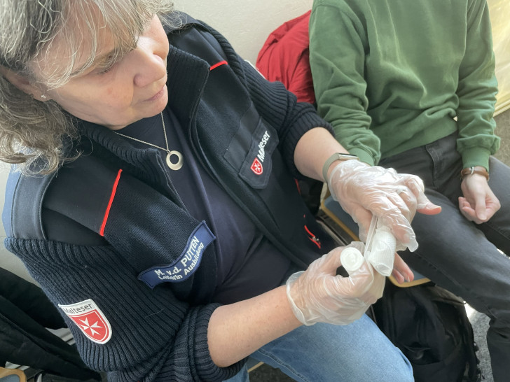 Marion van der Pütten zeigt, wie man mit professionellen Mitteln einen Verband anlegt. Im Notfall muss es auch mit improvisierten Mitteln gehen.