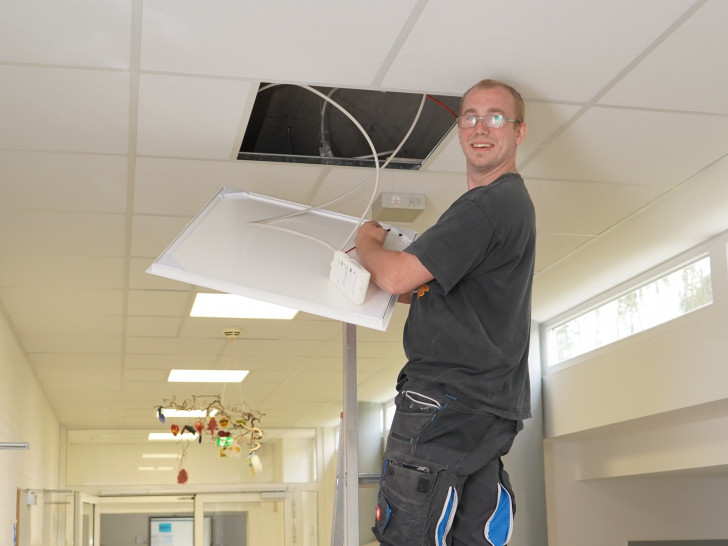 Ein Mitarbeiter des Bauwirtschaftshofs der Gemeinde Ilsede nimmt den Einbau der Beleuchtung in der Grundschule vor.