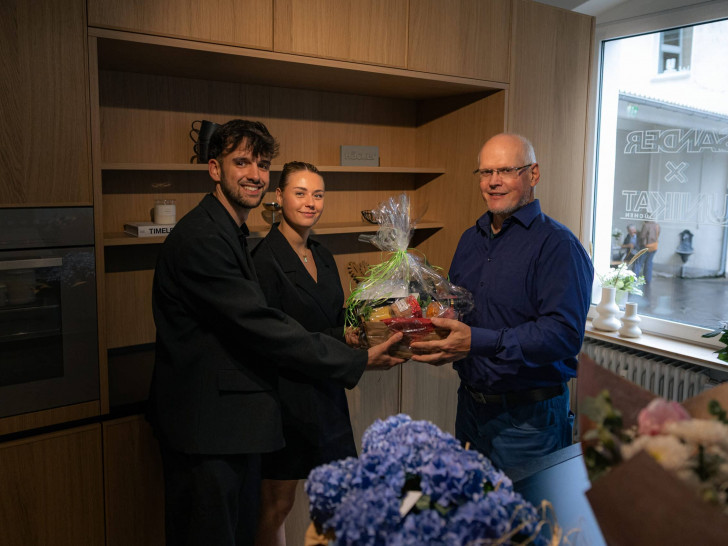 Die Gründer Tim Deichmann und Sina Joost erhalten ein Einzugsgeschenk von Rainer Müller, der bei Garant Gründungen betreut.