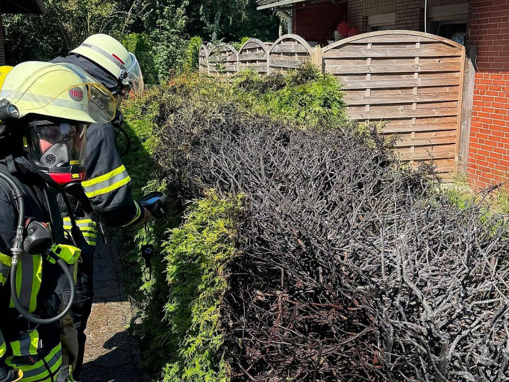Atemschutzgeräteträger der Feuerwehr Haxtum kontrollierten die bereits durch Anwohner erfolgreich gelöschte Hecke nach. (Archiv)