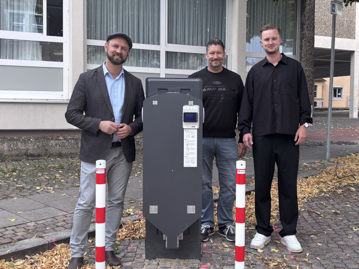 Bürgermeister Malte Schneider, Kai Engel und Lukas Grebener, Wirelane GmbH, präsentieren den Ladepunkt am Neuen Rathaus.